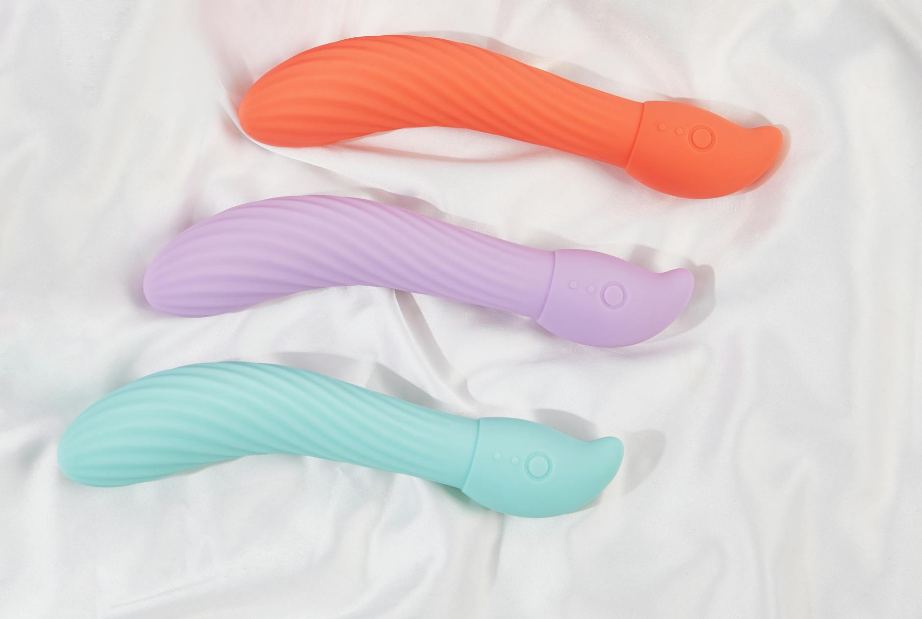 Three colorful lemon-shaped vibrators arranged on soft white fabric