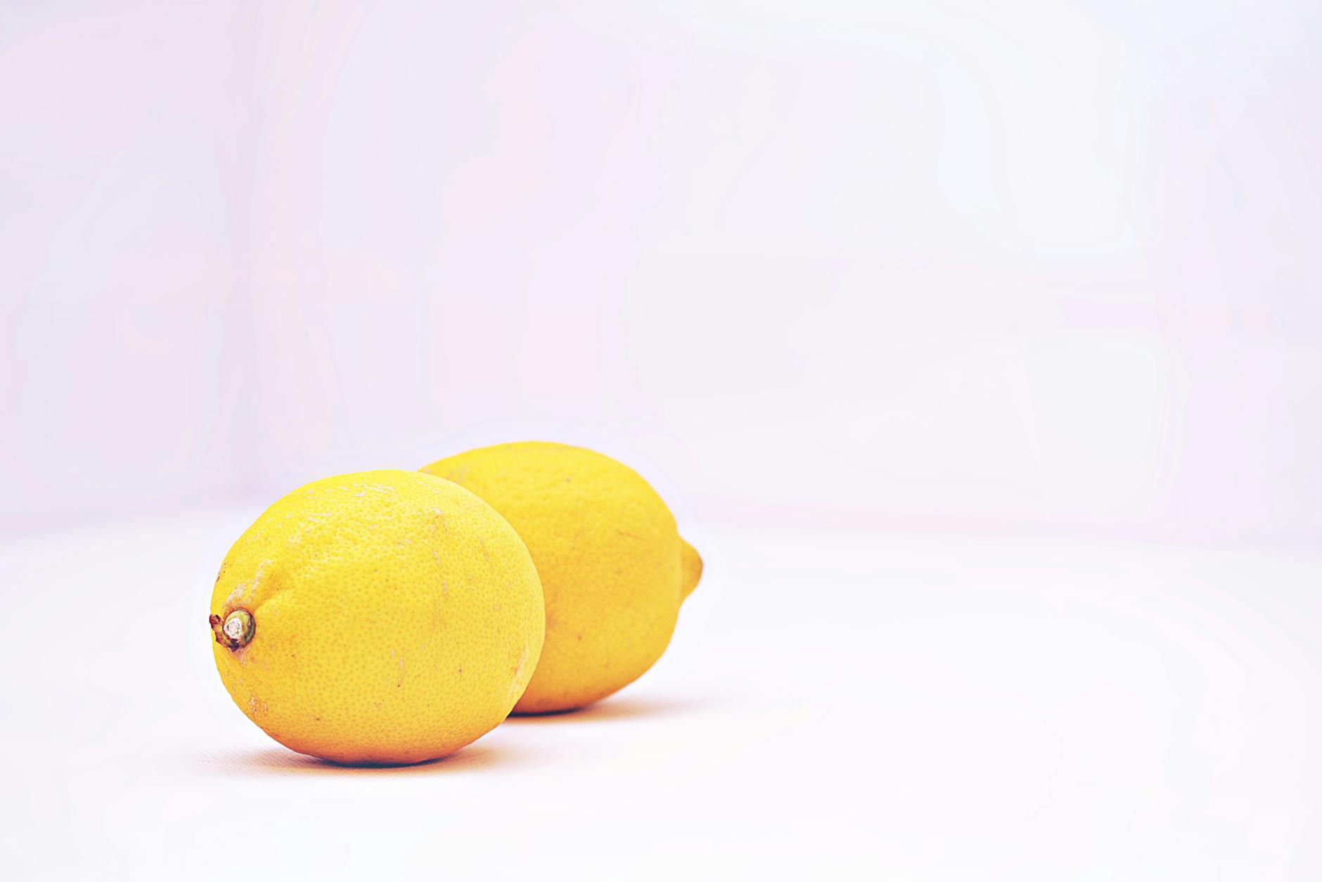Dos limones vibrantes colocados sobre un fondo blanco minimalista, mostrando frescura y simplicidad