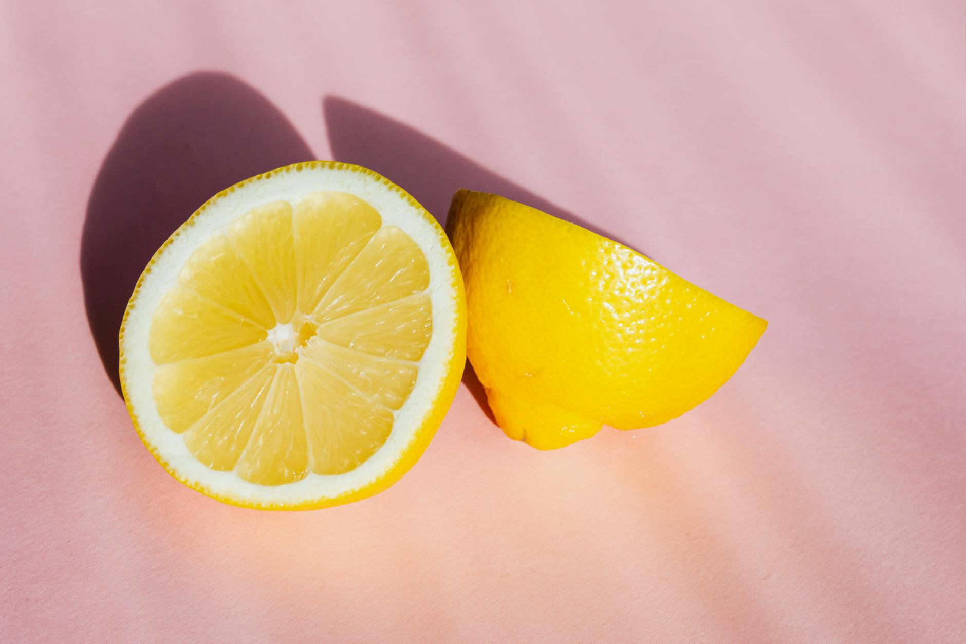 Una mano sosteniendo un limón fresco contra un fondo amarillo brillante