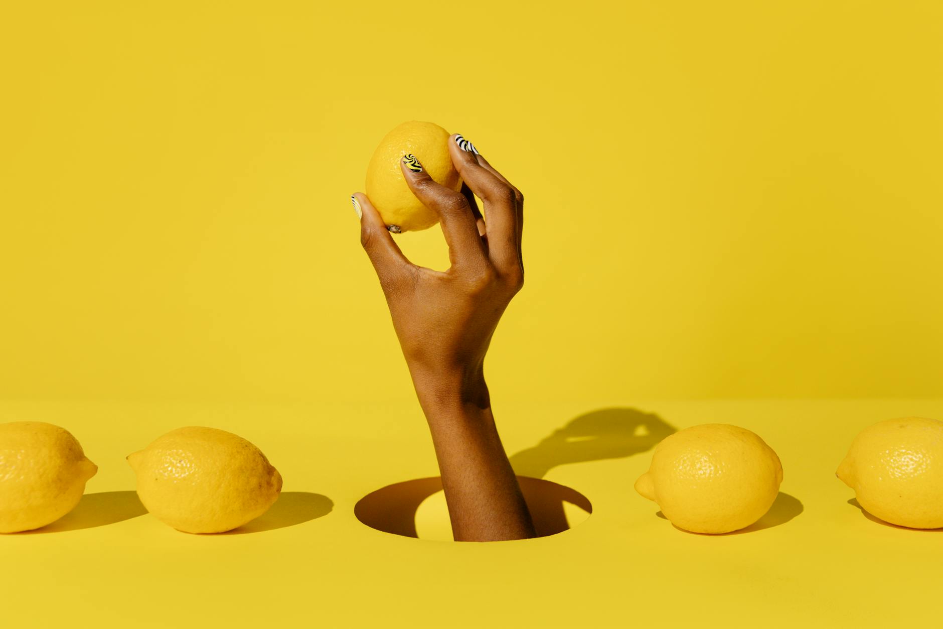 A hand holding a fresh lemon against a bright yellow background, symbolizing awakening and citrus freshness