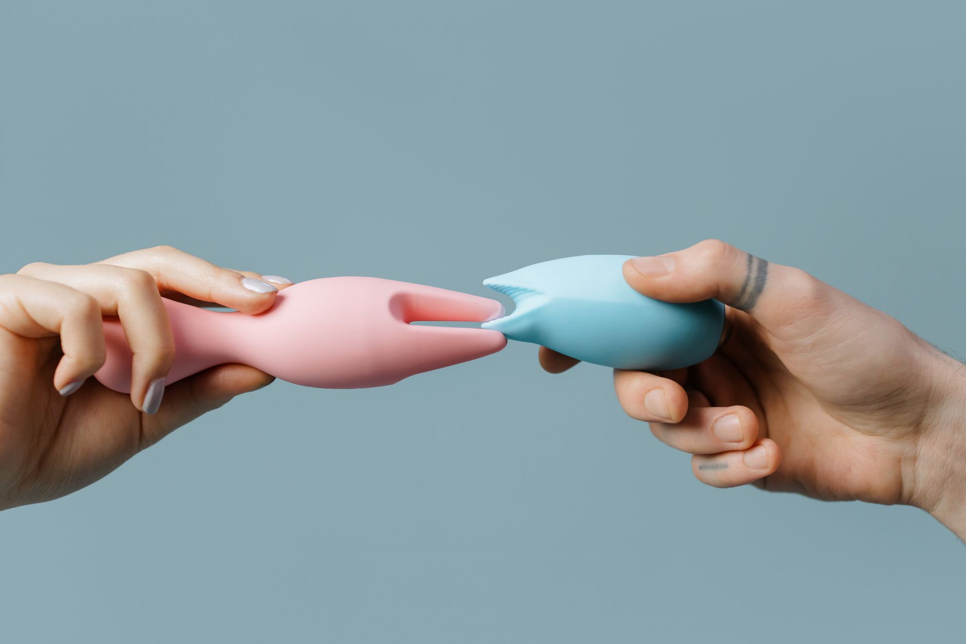 Hands holding colorful silicone toys on neutral background