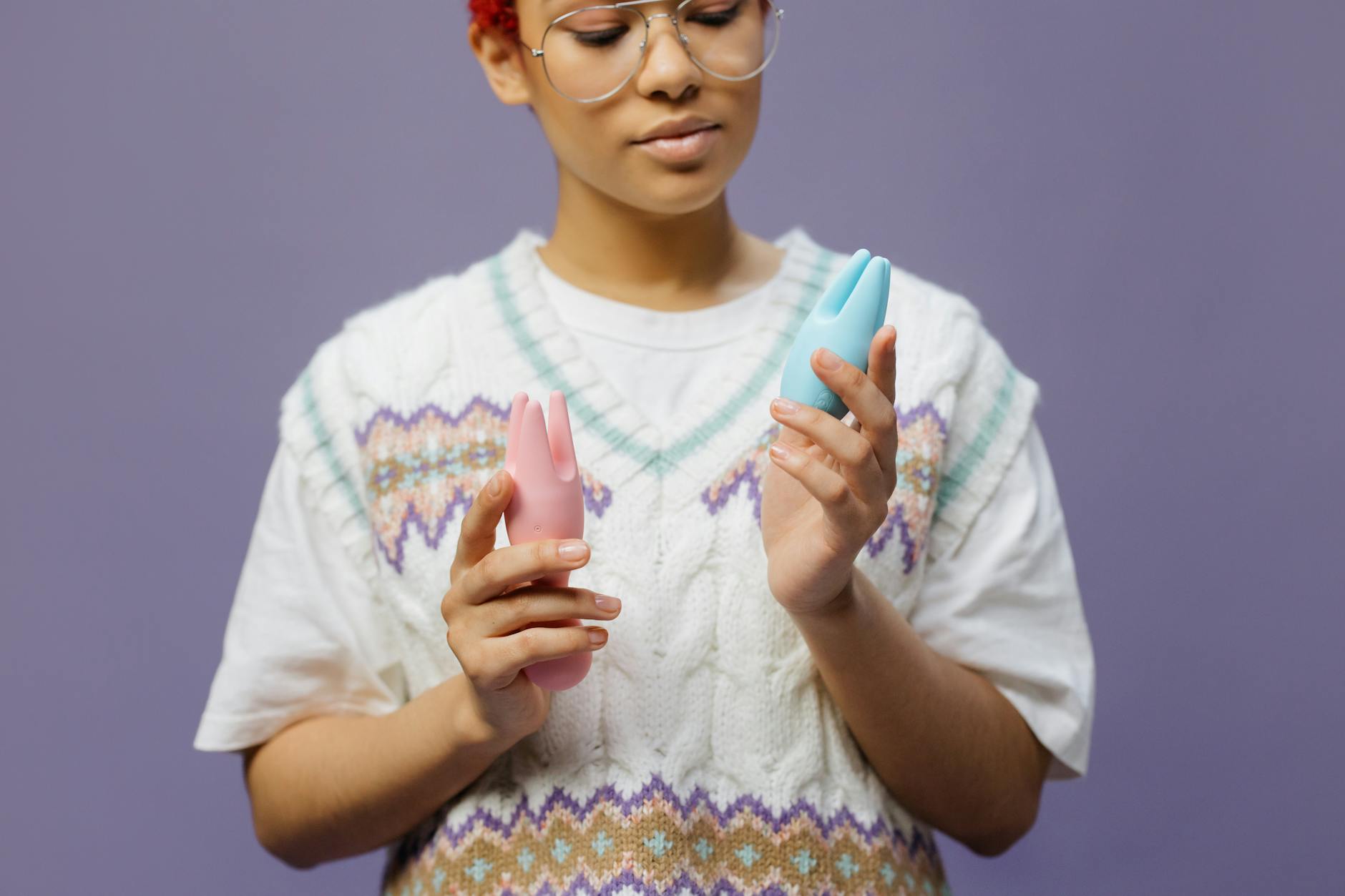 Woman thoughtfully holding a blue silicone clitoral vibrator