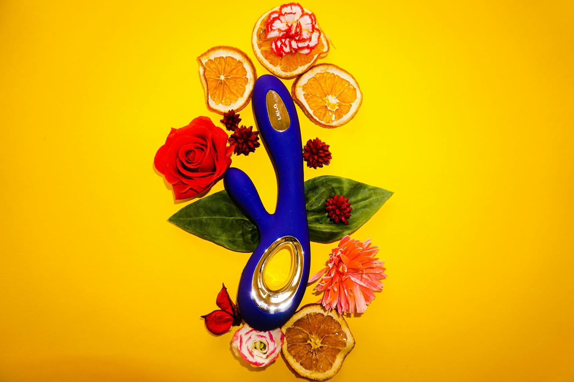 Lemon vibrator surrounded by flowers and citrus on a bright yellow background