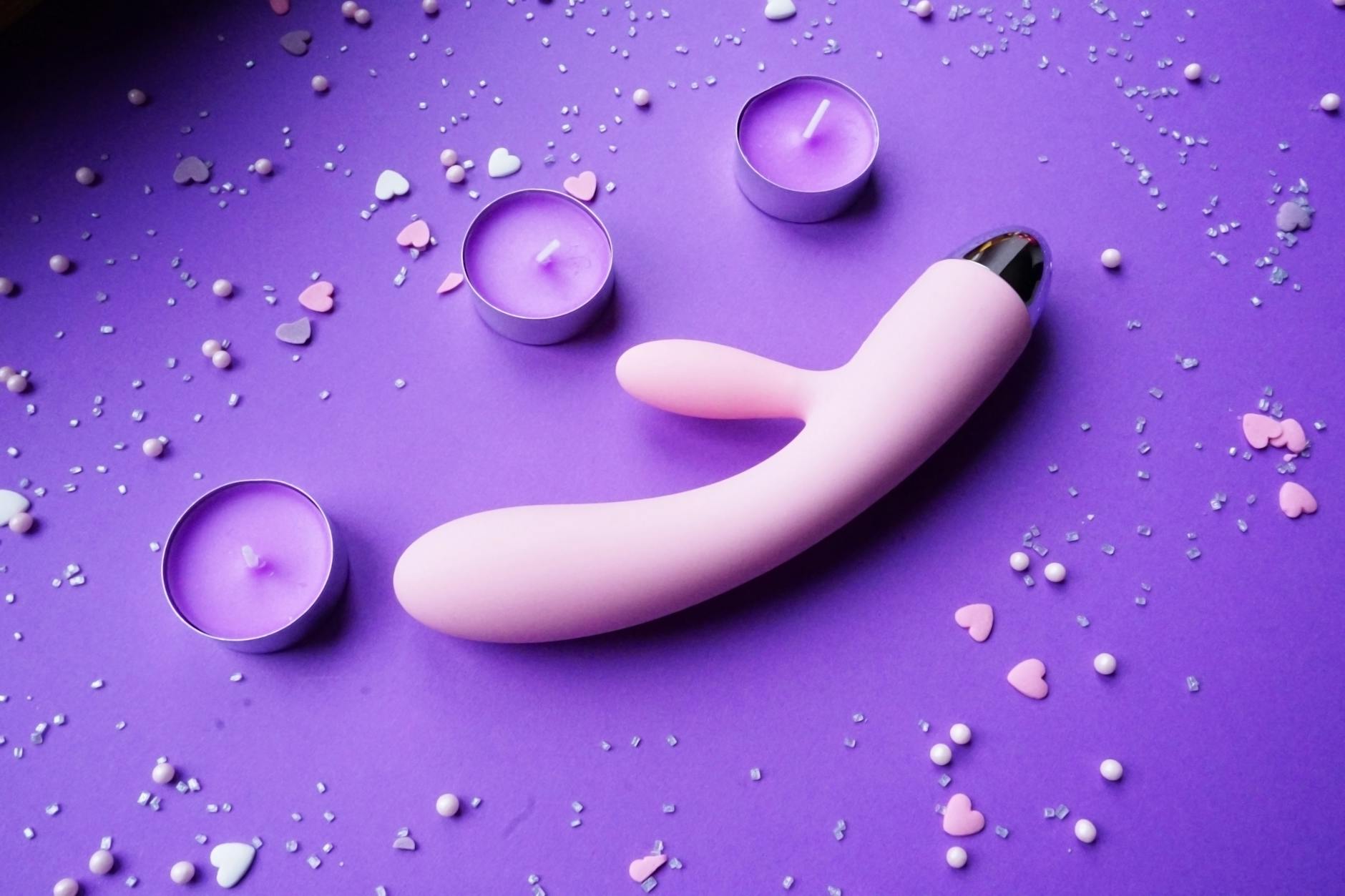 A silicone vibrator held gently in hand against a solid background, symbolizing safe touch and self-care for sensitive bodies